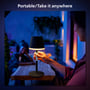 Person tager Philips Hue Go bordlampen med ud i mørket, hvor den lyser varmt, tekst 'Portable/Take it anywhere'.