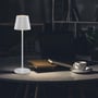 V-TAC mini bordlampe tændt på et rundt bord med bøger og en kaffekop, hvilket skaber en hyggelig atmosfære på et hjemmekontor.