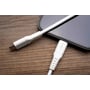 Hvidt FIXED USB-C til Lightning-kabel ved siden af en telefon på en træflade, med begge stik synlige.