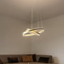 SLV One Double pendel i messingfarvet aluminium med to ringe, monteret i et hjørne med sofa i baggrunden.