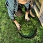 Person placerer græs i GreenCover havedæksel, viser integration med omgivelserne.