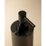 Nærbillede af top og pumpe på Cosmic sæbedispenser i mat sort metal, med logo synligt.