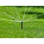 Gardena Pop-up sprinkler MD40 i aktion, sprinkleren vander en frodig grøn græsplæne med fine vandstråler.