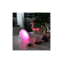 Genopladelig RGB+CCT-bordlampe lyser pink på et bord med dekorationer og glas.