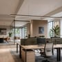 SpectrumLED kontorlampe hænger over skriveborde i et lyst kontor med glasvægge og grønne planter.