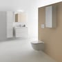 Laufen Base-spejlskab monteret på en beige badeværelsesvæg ved siden af håndvask og toilet.