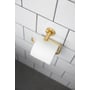 Elegant HeFe toiletpapirsholder i skinnende messing, monteret på en hvid, flisebelagt væg, med toiletpapir påsat.