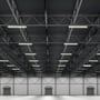 Flere V-TAC LED-armaturer lyser monteret under loftet i en stor lagerhal.
