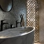 Elegant badeværelsesdesign med marmorbordplade, mørke vandhaner og et dekorativt mosaikbaggrund.