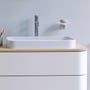 Nærbillede af en Duravit D.2 Plus vask på en mat hvid bordplade med poleret krom vandhane, der fremviser en ren og elegant finish.