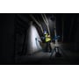 Bosch GLT 18V-5000 arbejdslampe står tændt på et stativ og oplyser en håndværker i et mørkt rum.