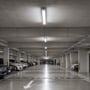 V-TAC LED-armaturet lyser fra loftet i en parkeringskælder med biler på begge sider.