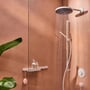 Hansgrohe Pulsify S håndbruser i mat hvid, med PowderRain stråle, vist i et moderne badeværelse med orange vægge og grøn plante.