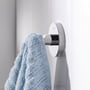 Grohe Essentials håndklædekrog i krom monteret på en hvid badeværelsesvæg med et blåt frottéhåndklæde hængende på.