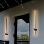 To V-TAC LED væglamper monteret på en udendørs væg ved en døråbning, der afgiver et varmt, indirekte lys.