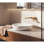 Grohe Lineare håndvaskarmatur i børstet warm sunrise monteret over en fritstående håndvask på badeværelset.