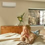 Daikin Nepura Comfora 35-indedel monteret højt på væggen i et soveværelse, mens en kvinde slapper af.