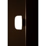 Ifö Electric Solenne loft- og væglampe i sort med mat opalglas, vist tændt på en mørk væg.
