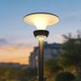 V-TAC Lotus LED-solcellehavelampe lyser varmt fra en sort stander i en have ved solnedgang.