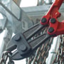 Detaljebillede af Knipex boltsaksen i brug, hvor den klipper en kraftig metalkæde i et industrielt miljø.