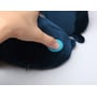 Fingre trykker på den blå knap på Travel Blue Massage Tranquility nakkepuden i mørkeblå velour.