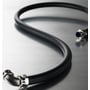 Fleksibel sort HellermannTyton Ø10 GS/PVC/glat slange med metalfittinger, der snor sig på en reflekterende overflade.