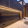 SLC LED strip monteret langs en mørk garageport og indgangsparti, skaber varmt lys i snevejr.