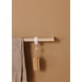 Detalje af en beige Metallbude Vana håndklædestang, der holder en lille kropsbørste med træskaft.