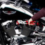 Knipex møtriktang holder en bolt på en motorcykel; tangens røde kæber viser sig tydeligt mod det blanke metal.