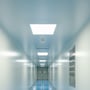 V-TAC 60 x 60 LED-panel lyser indbygget i loftet i en lang, lys gang med flere loftpaneler.