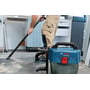 Bosch GAS 18V-10L Professional-støvsuger står på gulvet, mens en person støvsuger i et lyst værksted.