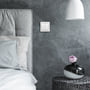 Nærbillede af Jumitech Zigbee Touchlink tryk med 4 hvide taster monteret på en mørk, tekstureret væg i et soveværelse.