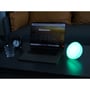 Genopladelig RGB+CCT-bordlampe lyser turkis ved siden af en bærbar computer i et mørkt rum.