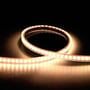 Ansell Lighting K-Cell LED bånd 50m, 24V, 3000K varm hvidt lys oplyst på mørk baggrund, viser lysstyrken og fleksibiliteten.