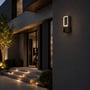 V-TAC LED-væglampe i mørkt aluminium lyser på husfacaden ved en udendørs indgang og trappe.