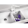 Nærbillede af Blanco Naya 8 S UX køkkenvask med hvid hane, hvor en kurv med lilla service og piskeris er placeret i den ene vask.
