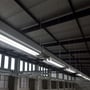 Montering af V-TAC Pro T8 LED lysrør i en industriel lagerhal med lang række af lysarmaturer.