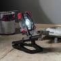 Coast CL40R LED arbejdslampe med clip-fod, oplyser et arbejdsområde med maling og værktøj i baggrunden.