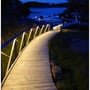 LEDlife LED-strip Type Q lyser langs rækværket på en gangbro ved vandet i mørke.