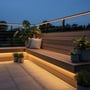 LEDlife vandtæt slim COB LED strip monteret langs en træterrasse og bænk i mørket, skaber stemningsfuld belysning.