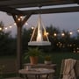 Trekantet hvid LED lanterne hænger fra en pergola over en havemøbelgruppe med tændte lyskæder.