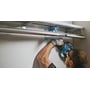 Bosch GSA 18V-32 bajonetsav bruges under en metalhylde, hvor en person saver i et rør på et trangt sted.