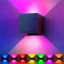 En LEDlife Cubic væglampe lyser op med lyserøde nuancer, flankeret af et udvalg af farvede lyskuber, der viser RGB-funktion.