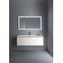 Duravit L-Cube underskab med et udtræk, monteret under en vask med krom vandhane, oplyst spejl bagved på betonvæg.