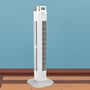 En hvid V-TAC LED tårnvifte står på et trægulv med en blå bagvæg, viser et rent design.