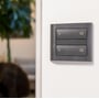Koksgrå ZigBee tryk til lysstyring monteret på hvid væg, med to vippekontakter til On/Off funktion.