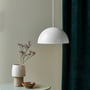 Nordlux Ellen pendel i hvid metal og plast, vist i et nordisk interiør med en vase på et sidebord.
