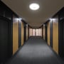 V-TACs runde LED-sensorlampe lyser i loftet på en lang gang med mørke vægge.