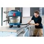 Bosch GAS 18V-10L Professional-støvsuger står på en arbejdsbænk, mens en håndværker støvsuger ved bordkanten.