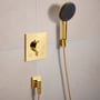 Hansgrohe Raindance Alive Select S brusesæt i skinnende guld med grafitfarvet brusertallerken monteret på en lys, neutral væg.